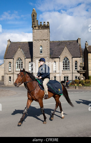 Saslong horse rider on road.  Exercising Racehorses on road, in the Town of Middleham, North Yorkshire Dales, UK Stock Photo