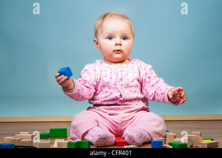 Infant child playing with bricks on wooden floor Stock Photo