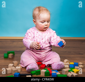 Infant child playing with bricks on wooden floor Stock Photo