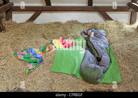 two children sleeping in a haystack Stock Photo