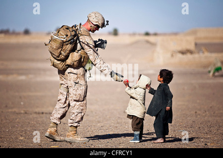 U.S. Marine Lance Cpl. Tom Morton hands an Afghan child a toy during a security patrol February 25, 2012 in Safar Bazaar, Afghanistan. Stock Photo