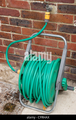 Hose pipe on reel attached to outside tap in garden with the hosepipe ban in force in many areas of the country Stock Photo
