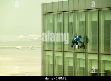 Hanging window cleaner at Beijing Airport with an aircraft on the background, China Stock Photo