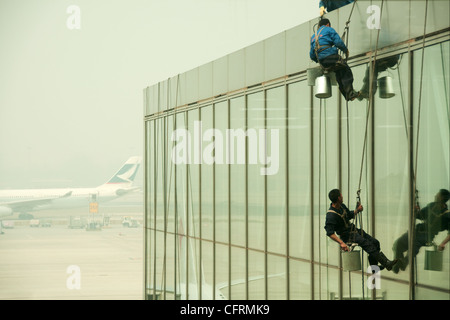 Hanging window cleaners at Beijing Airport with an aircraft on the background, China Stock Photo