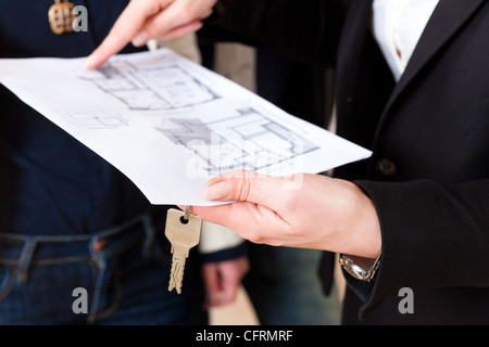 Young realtor explain lease agreement or purchase contract with floor layout to couple in an apartment, close-up Stock Photo