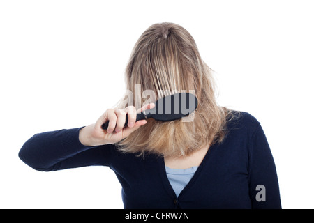 Young woman covered her face with hair using hairbrush, isolated on white background. Stock Photo
