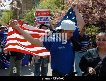 An unidentified protester carries an American flag as Hundreds of immigrant community members rally in Washington Square Park and march up Broadway to highlight the humanitarian crisis created by immigration raids, deportations, and the failure of the federal government to enact immigration reform.  Stock Photo