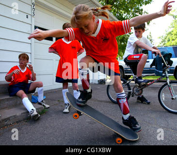 Buffalo, MN  6/17/20003 Kendra Durst, 10, takes a spin on a skateboard in the diveway before heading to a socer game with her sisters.  The girls are all on the same team.  Sarah (Back left), Calli (Back Center) and neighbor Nathan Engfer (on bike) (Credit Image: © Minneapolis Star Tribune/ZUMA Pres Stock Photo