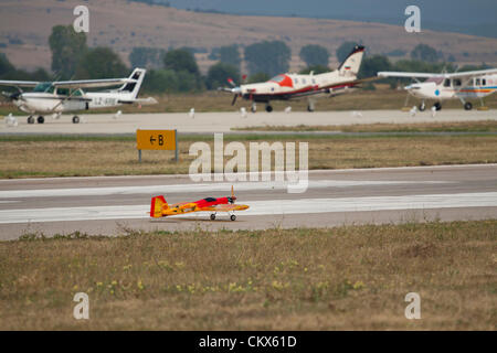 Lesnovo, Bulgaria; 24th Aug 2012. Remote-controlled scale model on the runway at Lesnovo airport with its full-sized cousins in the background. Credit:  Johann Brandstatter / Alamy Live News Stock Photo