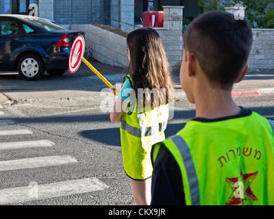 27th Aug 2012. Sixth grade students perform the services of traffic monitoring and assisting younger students in safe access to Yeffe-Nof Elementary School. Jerusalem, Israel. 27-Aug-2012.   Israeli children go back to school today, abolishing traditional Sept. 1st date, in a first stage of reforms initiated by Ministry of Education aiming to shorten summer vacation to 6 weeks, partially relieving parents of enormous financial expenses. Stock Photo