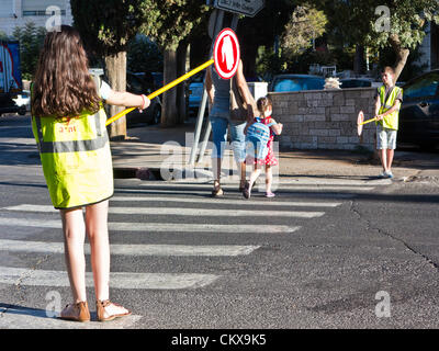 27th Aug 2012. Sixth grade students perform the services of traffic monitoring and assisting younger students in safe access to Bet-Hakerem Elementary School. Jerusalem, Israel. 27-Aug-2012.   Israeli children go back to school today, abolishing traditional Sept. 1st date, in a first stage of reforms initiated by Ministry of Education aiming to shorten summer vacation to 6 weeks, partially relieving parents of enormous financial expenses. Stock Photo