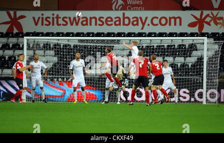 Liberty Stadium, Swansea, UK. 28th Aug 2012.   Pictured: Alan Tate of Swansea (in white TOP) heads the ball away from a Barnsley cross. Capital One Cup game, Swansea City FC v Barnsley at the Liberty Stadium, south Wales, UK. Credit:  D Legakis / Alamy Live News Stock Photo