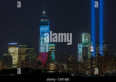 The twin beams of light of the Tribute in Light, an annual remembrance of the events of September 11, 2001, shine into the night sky in New York City over the skyline of lower Manhattan.  This view of the skyline includes two symbols of freedom, the Statue of Liberty and the Freedom Tower (One World Trade Center). Stock Photo