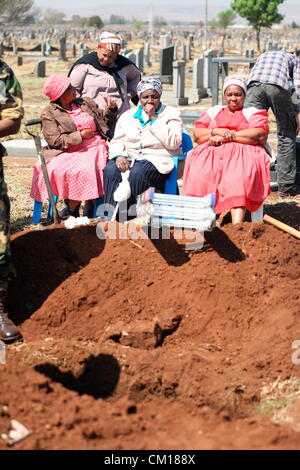 Soweto, South Africa. 11th September 2012. Family members watch as bones believed to be those of Nceba Sinuma are exhumed on September 11, 2012 at Avalon Cemetery in Soweto, South Africa. Sinuma was one of the “Mofolo 3” who were killed by apartheid agents in a security operation in 1989. The Mofolo 3 were members of the Soweto Youth Congress and were involved in underground uMkhonto weSizwe activities. The body exhumed will be sent for DNA testing. (Photo by Gallo Images / Sowetan / Vathiswa Ruselo/Alamy Live News) Stock Photo