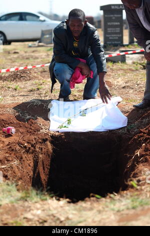 Soweto, South Africa. 11th September 2012. Sandile Sinuma watches as bones believed to be those of his brother, Nceba Sinuma are exhumed on September 11, 2012 at Avalon Cemetery in Soweto, South Africa. Sinuma was one of the “Mofolo 3” who were killed by apartheid agents in a security operation in 1989. The Mofolo 3 were members of the Soweto Youth Congress and were involved in underground uMkhonto weSizwe activities. The body exhumed will be sent for DNA testing. (Photo by Gallo Images / Sowetan / Vathiswa Ruselo/Alamy Live News) Stock Photo