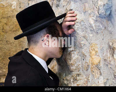 A man buries his head in the stones of the Western Wall as he prays on the Eve of the Jewish New Year, Rosh Hashanah. Jerusalem, Israel. 16-September-2012.  Thousands pray at the Western Wall on the Eve of the Jewish New Year for the last time in the year 5772. According to the Jewish calendar the year 5773 and the Jewish High Holidays will begin tonight after sunset. Stock Photo