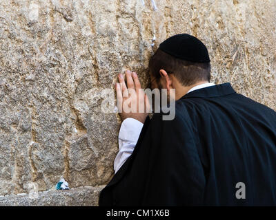 A man buries his head in the stones of the Western Wall as he prays on the Eve of the Jewish New Year, Rosh Hashanah. Jerusalem, Israel. 16-September-2012.  Thousands pray at the Western Wall on the Eve of the Jewish New Year for the last time in the year 5772. According to the Jewish calendar the year 5773 and the Jewish High Holidays will begin tonight after sunset. Stock Photo