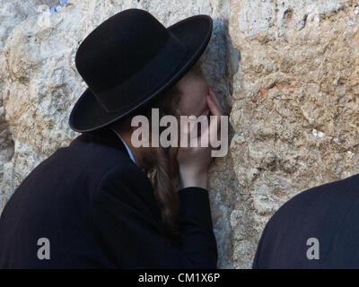 A man buries his head in the stones of the Western Wall as he prays on the Eve of the Jewish New Year, Rosh Hashanah. Jerusalem, Israel. 16-September-2012.  Thousands pray at the Western Wall on the Eve of the Jewish New Year for the last time in the year 5772. According to the Jewish calendar the year 5773 and the Jewish High Holidays will begin tonight after sunset. Stock Photo