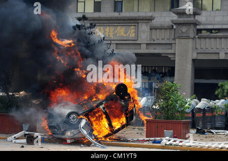 Xian, China. Saturday 15th September, 2012. Anti-Japanese protesters burn a car during a demonstration at Bell Tower Hotel in Xi'an,China,on Saturday Sept 15, 2012.  Fights broke out between demonstrators and police during a march by more than 10,000 students, who were protesting at the sovereignty of the Fishing Islands(Diaoyu Islands). Stock Photo