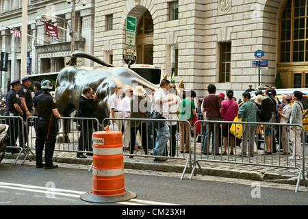 New York, NY, September 17, 2012. On first anniversary of Occupy Wall Street protests, police allow group of tourists to take pictures next to the famous charging bull statue near Wall Street, even though barricades kept protesters away from the statue Stock Photo