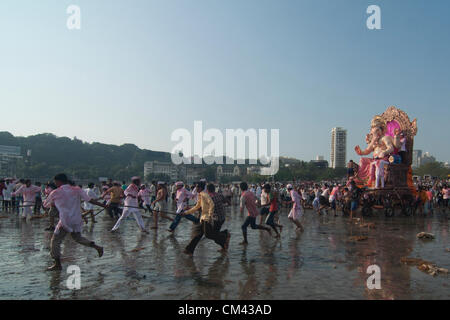 Mumbai, India. Indian Hindu devotees carry around a huge idol of the elephant-headed Hindu god Lord Ganesha on the beach for immersion of the idol into the Arabian Sea of Mumbai on September 29, 2012. People celebrate Ganpati (rebirth) of Lord Ganesh the Elephant God. Lasting for 10days, this custom culminates with the ritual emersion of Ganesh idols in local rivers and lakes. Stock Photo