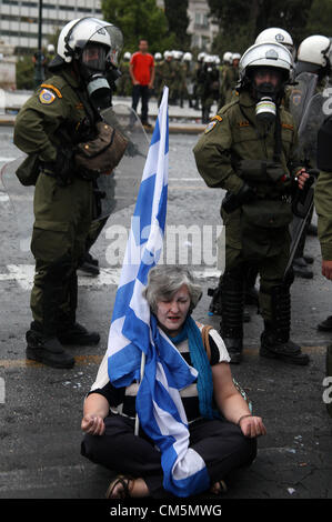 Athens, Greece. Tuesday 09 October 2012  Pictured: A female protester sits on the ground by riot police officers in Syntagma Square, infront of the Greek Parliament.  Re: German Chancellor Angela Merkel has pledged her country's continuing support to Greece, during her first visit to Athens since the eurozone crisis erupted nearly three years ago.  Mrs Merkel said Greece had made good progress in dealing with its vast debt but that it was on a 'difficult path'.  Thousands of people who blame Germany for forcing painful austerity measures on Greece are protesting in Athens.  Police have used te Stock Photo