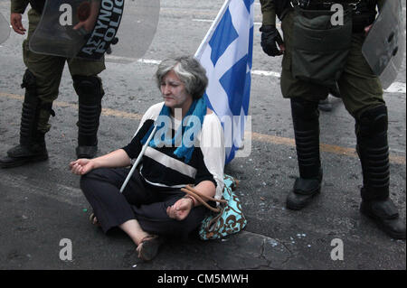 Athens, Greece. Tuesday 09 October 2012  Pictured: A female protester sits on the ground by riot police officers in Syntagma Square, infront of the Greek Parliament.  Re: German Chancellor Angela Merkel has pledged her country's continuing support to Greece, during her first visit to Athens since the eurozone crisis erupted nearly three years ago.  Mrs Merkel said Greece had made good progress in dealing with its vast debt but that it was on a 'difficult path'.  Thousands of people who blame Germany for forcing painful austerity measures on Greece are protesting in Athens.  Police have used te Stock Photo