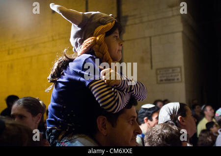 A young girl on her father’s shoulders watches a performance in one of the Christian Quarter’s alleys at the Knights of the Night Festival. Jerusalem, Israel. 18-October-2012.  Third annual Old City Knights Festival opens and will run for four consecutive Thursdays. This year's theme is knights and dragons and features battle scenes between knights and fire spitting dragons, princesses and jesters. Stock Photo