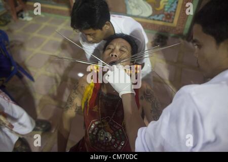 Oct. 19, 2012 - Phuket, Thailand - A man with various blades pierced through his skin before a street procession at the annual Vegetarian Festival. The annual tradition sees devotees of the Chinese shrine of Ban Tha Rue emphasize merit making and ritual cleansing of the body to mark the nine-day-long festival featuring face-piercing, spirit mediums, and strict vegetarianism. (Credit Image: © David Longstreath/ZUMAPRESS.com) Stock Photo