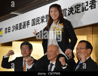 October 23, 2012, Tokyo, Japan - Saori Yoshida, Japan's three-time Olympic wrestling champion, rides on the shoulders of her coach Kazuhito Sakae, posing for photographers after a news conference in Tokyo on Tuesday, October 23, 2012. Japanese government decided to bestow the People's Honor Award on her for 'bringing hope and courage to society.' Yoshida,30, won a total of 13 Olympic and world titles in women's wrestling. Others are Yukiyasu Aoyama, left, Yoshida's employer, and Tomiaki Fukuda, president of the Japan Wrestling Federation. (Photo by Natsuki Sakai/AFLO) AYF -mis- Stock Photo