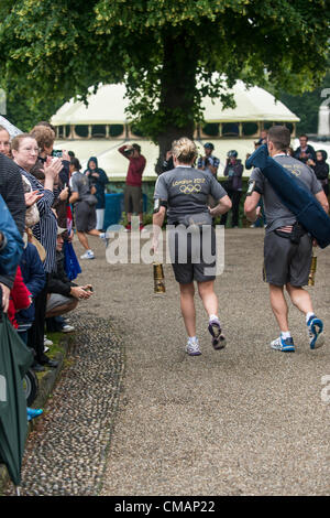 Ipswich, UK. Friday 6th July 2012. Emily Rogers from Bury St. Edmunds starts off day 49 of the Olympic Torch Relay. The Olympic Torch starts in Ipswich and makes its way to Essex. Olympic Flame in lantern being carried by two wardens. Stock Photo