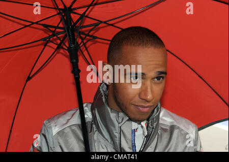 06.07.2012 Towcester, England.  British Formula One driver Lewis Hamilton of McLaren Mercedes walks through the pit lane sheltering under an umbrella during the second practice session at the Silverstone race track in Northamptonshire, Great Britain, 06 July 2012. The Formula One Grand Prix of Great Britain will take place on 08 July 2011. Stock Photo