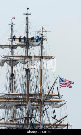 US Coast Guard cadets furl the sails on America's tall ship Eagle as it docks at its home port of Fort Trumbull, New London, CT where it can often be seen in the summer. The Eagle is the only active-duty sailing ship in America's military.  An American flag flies from the stern. Copy space. Original Live News Caption: New London, Connecticut, USA - July 7, 2012: The US Coast Guard tall ship Eagle lands at Fort Trumbull during the OpSail 2012 festival. Cadets high up in the rigging furl the sails after the Parade of Sail during festivities commemorating the bicentennial of the War of 1812. Stock Photo