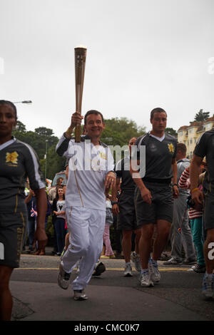 Bournemouth, UK Friday 13 July 2012. Olympic Torch Relay at Bournemouth, UK - runner Ian Kennedy, Wimborne Athletics Club coach, takes the torch into the Lower Gardens at Bournemouth on Friday evening Stock Photo