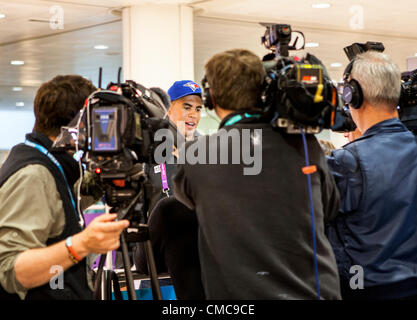 Heathrow Airport, London, UK 16th July 2012: Greg Douglas, Canadian Olympic sailor  is interviewed by journalists as he leaves the arrivals area at Heathrow AIrport Terminal 3 this morning. Douglas beat veteran sailor Chris Cook of Whitby at the last Olympic qualifier in Falmouth, England on the 18th May 2012 and grabbed the only Olympic place for Canada in the Finn class. Heathrow airport is prepared  for an influx of Olympic athletes, officials and tourists. It was forecast that today would see a huge increase of travllers arriving at Heathrow and all doors were manned by London 2012 Olympic Stock Photo