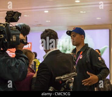 Heathrow Airport, London, UK 16th July 2012: Greg Douglas, Canadian Olympic sailor  is interviewed by journalists as he leaves the arrivals area at Heathrow AIrport Terminal 3 this morning. Douglas beat veteran sailor Chris Cook of Whitby at the last Olympic qualifier in Falmouth, England on the 18th May 2012 and grabbed the only Olympic place for Canada in the Finn class. Heathrow airport is prepared  for an influx of Olympic athletes, officials and tourists. It was forecast that today would see a huge increase of travllers arriving at Heathrow and all doors were manned by London 2012 Olympic Stock Photo