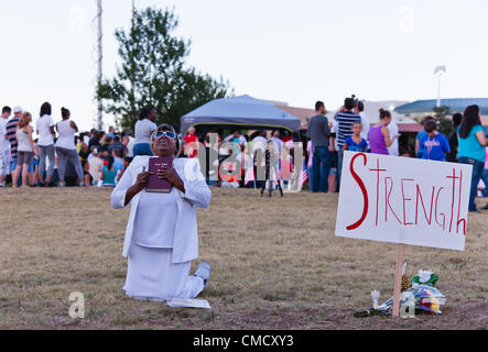 Aurora, Colorado, USA. 20th July, 2012. A crowd gathers for an impromptu prayer vigil across the street from the Century 16 Theater on July 20, 2012. Marietta Perkins from Mary Sanctuary prays for the shooting victims. Stock Photo