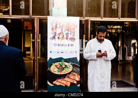 London, UK - 21 July 2012: A Muslim faithful stands by a billboard at the Ramadan Iftar 2012 celebrations hosted at the Islamic Cultural Centre (ICC) in Regents Park. Stock Photo