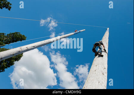 24th July 2012. Llanelwedd, Wales, UK. Contestants for the Welsh Open Speed Pole Climbing competition don a climbing harness and strap spiked trainers to their legs and feet to make a climbing assault on two perilous 100ft (30 metres approx) poles that rise up to the bright blue sky above from the Forestry Area at The Royal Welsh Showground where the 108th Royal Welsh Agricultural Show is taking place for four days this week at Llanelwedd in Mid Wales. Photo credit: Graham M. Lawrence/Alamy Live News