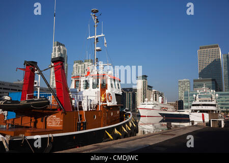 London, England, UK. Wednesday, 25 July 2012. Luxury yachts, tall ship Stad Amsterdam and the 'love boat' cruise liner MS Deutschland, home to the German Olympic team, are at anchor in West India Dock, Canary Wharf, London, for the Olympics. Stock Photo