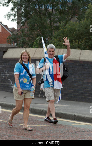 Manchester, UK. 26th July, 2012. Two supporters carrying the Uruguayan flag wave to the photographer on their way to the  first Olympic Games matches to be played at Old Trafford - United Arab Emirates v Uruguay and Great Britain v Senegal 26-07-2012 Stock Photo