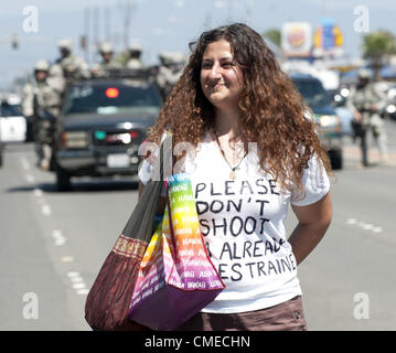 July 29, 2012 - Anaheim, California, USA - A young woman with a t-shirt that reads ''Please Don't Shoot,'' stands in the street on West Ball Road near the intersection with South Harbor Blvd.  Behind her Anaheim SWAT can be seen as they attempt to stop deomonstrators from reaching Disneyland to continue their protest...----Several hundred demonstrators gathered together in front of Anaheim Police Headquarters to protest two recent officer involved shootings including the shooting death of Manuel Diaz, 25, a little more than a week ago, on Saturday July 21, 2012.  Althought Anaheim Police have  Stock Photo