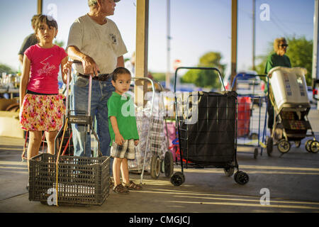 Aug. 7, 2012 - Tolleson, Arizona, U.S - Clients wait for the doors to open at the food bank in Tolleson, AZ, about 15 miles west of Phoenix. The Tolleson food bank has been operating for more than 20 years. It used to serve mostly the families of migrant farm workers that worked the fields around Tolleson but in the early 2000's many of the farms were sold to real estate developers. Now the food bank serves both farm worker families and people who lost their homes in the real estate crash, that his Phoenix suburbs especially hard. More than 150 families a day are helped by the Tolleson food ba Stock Photo