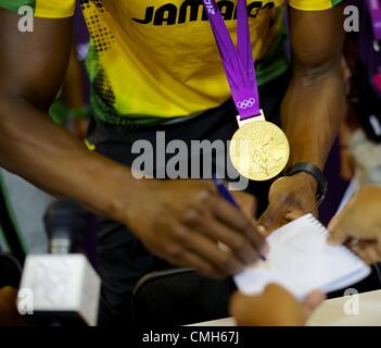 Aug. 9, 2012 - London, England, United Kingdom - Gold medal winner Jamaican sprinter USAIN BOLT signs autographs after participating in a press conference following his victory with teammates and silver and bronze recepients, Yohan Blake and Warren Weir, in Olympic Stadium, during the 2012 London Summer Olympics. (Credit Image: © Mark Makela/ZUMAPRESS.com) Stock Photo