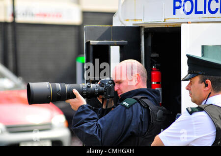 11 August 2012, Londonderry. PSNI officer photographing nationalist youths watching a loyalist parade. 10,000 Apprentice Boys of Derry and 120 bands took part in the annual Relief of Derry parade, the largest Loyal order parade held in Northern Ireland. Credit:  George Sweeney / Alamy Live News Stock Photo