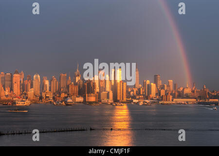 A rainbow appears over the midtown Manhattan skyline shortly after a summer thunderstorm, as the setting sun reflects off the windows of skyscrapers in New York City. Stock Photo