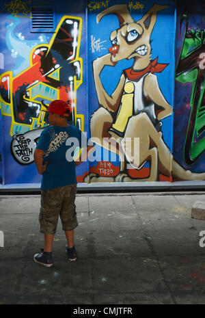 Bristol, UK. 18th August, 2012. A young boy stands looking at some of the art works painted on the outside of buildings in Nelson Street as part of the See No Evil Art project. Bristol,UK,on Saturday,18th August,2012. Stock Photo