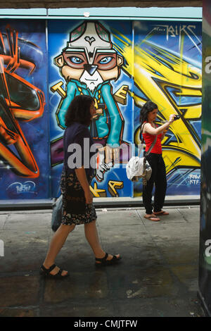 Bristol, UK. 18th August, 2012. A woman takes a photograph of artwork that has been painted on buildings in Nelson Street for the See No Evil street art festival. See No Evil is a collection of works of public art created by multiple graffiti and urban street artists which are located in and around Nelson Street in Bristol, UK. Stock Photo