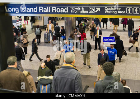 Manhattan, New York, U.S. 4th November 2013. TOM SUOZZI, Democratic candidate for Nassau County Executive, (R, in front on sign) meets potential voters descending the escalators during his campaign stop at Penn Station, near end of 36 straight hours of barnstorming across Nassau County, leading up to the November 5 general election. Former Nassau County Executive Suozzi and incumbent Republican Mangano are once again facing each other as challengers. Credit:  Ann E Parry/Alamy Live News Stock Photo