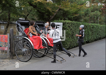 Japanese women sitting in rickshaws and their drivers, Kyoto, Japan Stock Photo